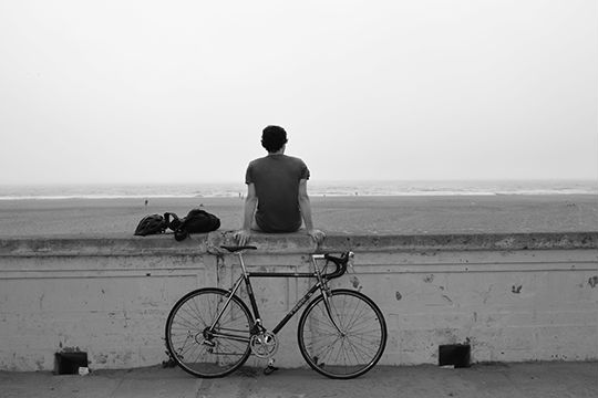 photo of a boy at the beach bicycle resting